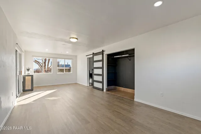 a view of an empty room with a window and wooden floor
