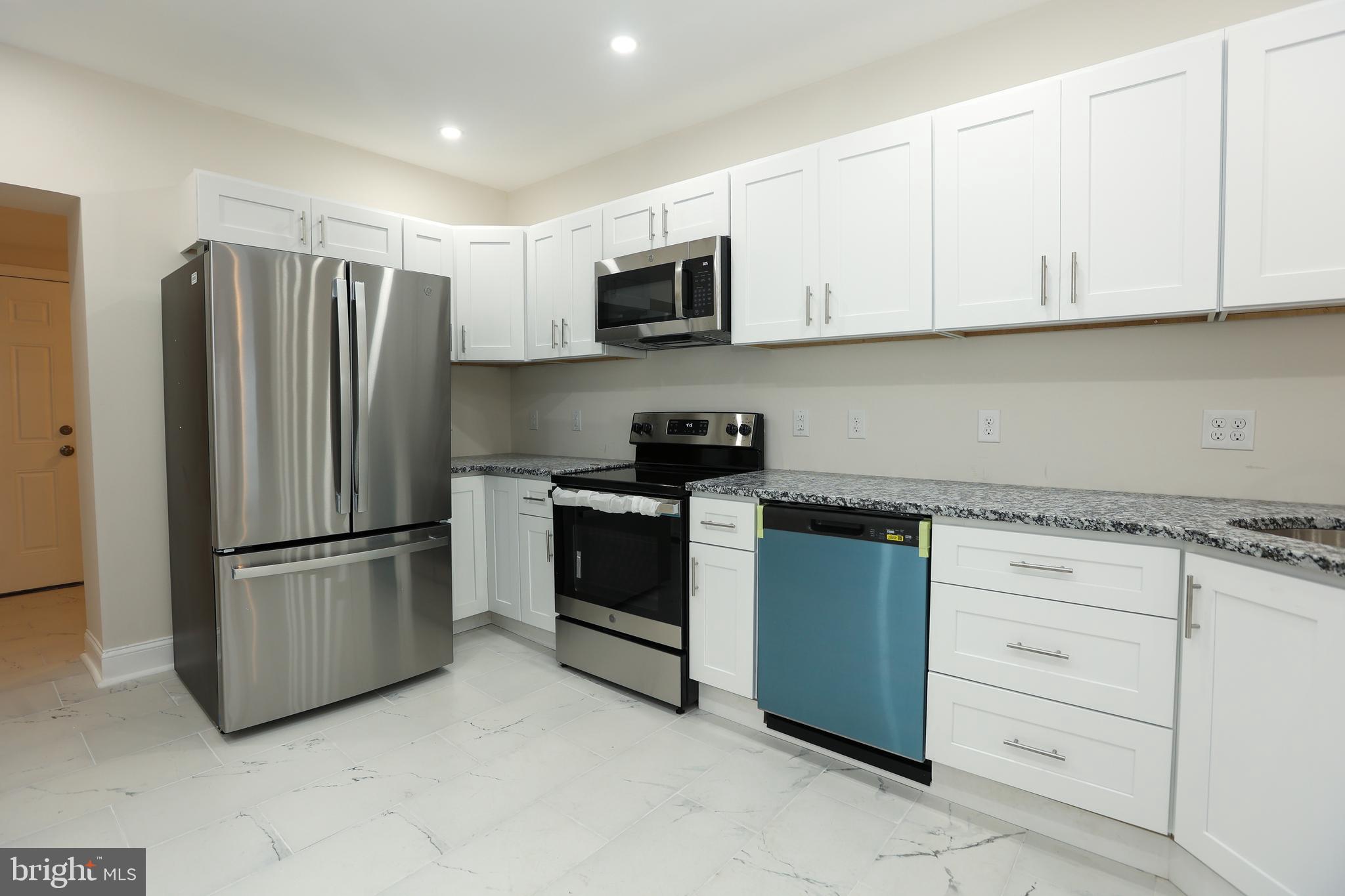 a kitchen with stainless steel appliances granite countertop white cabinets and a refrigerator