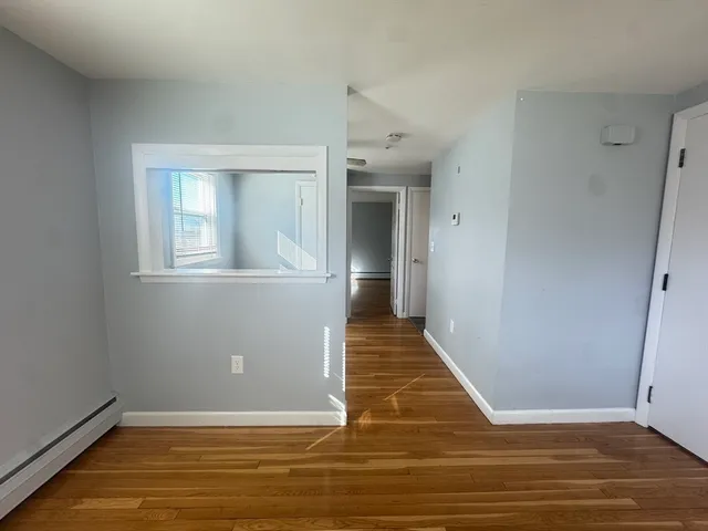 a view of an empty room with wooden floor and a window