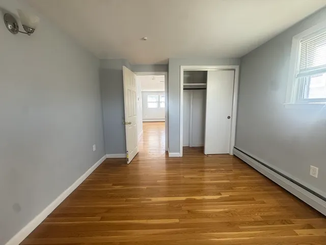 a view of an empty room with window and wooden floor