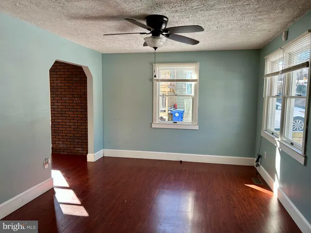 an empty room with wooden floor chandelier fan and windows