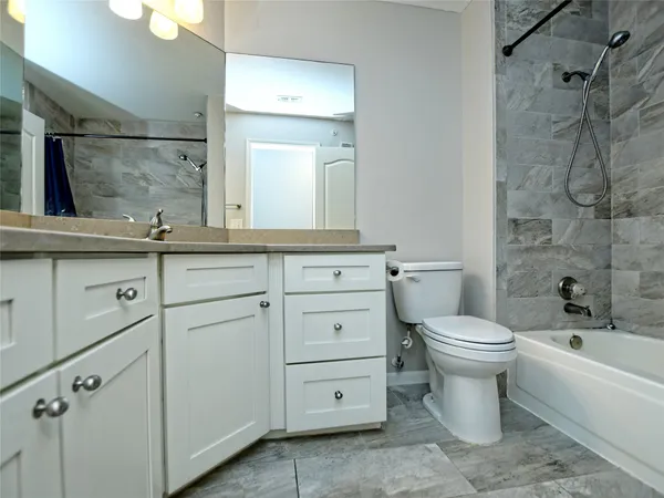 a bathroom with a granite countertop toilet sink and mirror