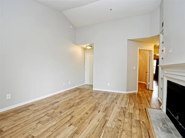 a view of empty room with wooden floor and fireplace