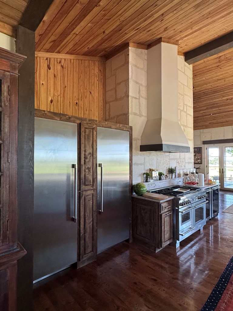 772 Luckenbach Road Fredericksburg, TX 78624 - Photo 19 of 87 a kitchen with stainless steel appliances granite countertop a refrigerator a stove and a wooden floors