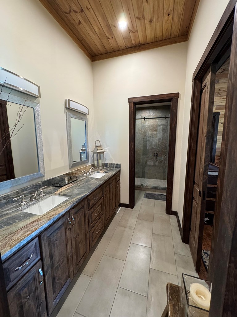 772 Luckenbach Road Fredericksburg, TX 78624 - Photo 43 of 87 a spacious bathroom with a granite countertop sink a mirror and a vanity