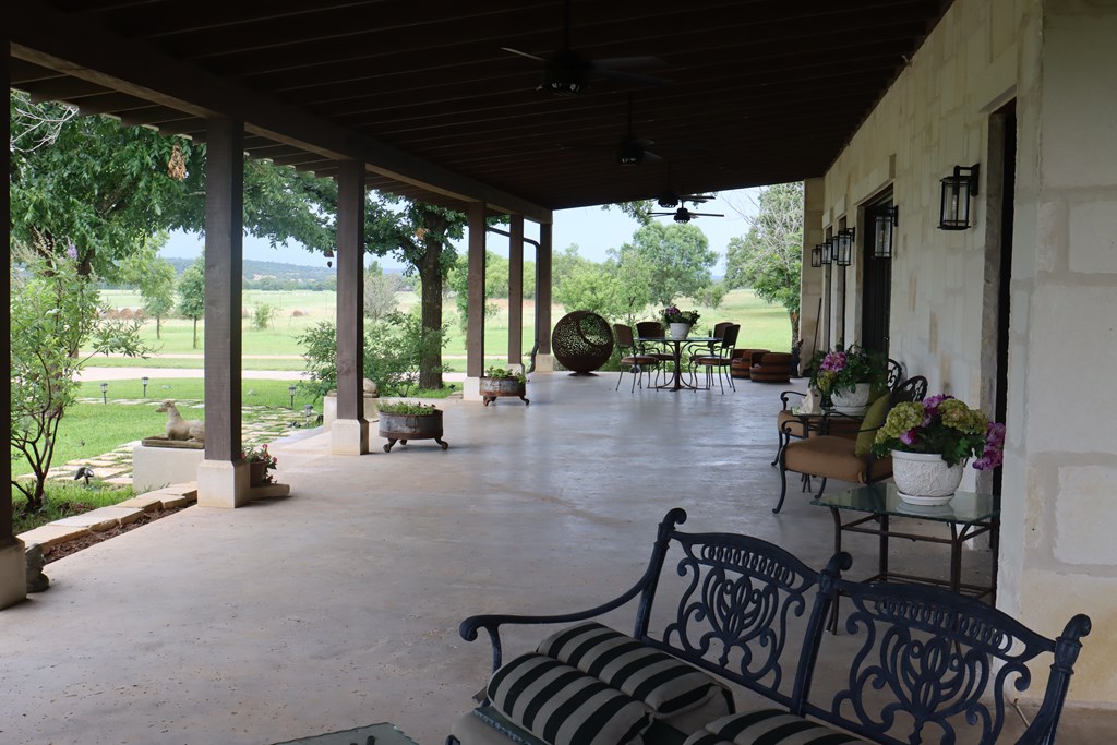 772 Luckenbach Road Fredericksburg, TX 78624 - Photo 7 of 87 a view of a patio with table and chairs potted plants with floor to ceiling window