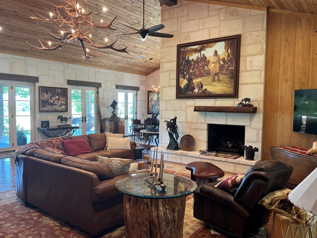 772 Luckenbach Road Fredericksburg, TX 78624 - Photo 10 of 87 a living room with furniture a fireplace and a flat screen tv