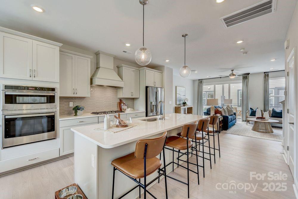 541 Annie Lowery Way Davidson, NC 28036 - Photo 7 of 29 a kitchen with stainless steel appliances kitchen island granite countertop a stove a sink a dining table and chairs with wooden floor