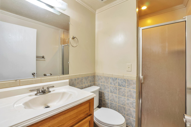 1057 North 700 West Clinton, UT 84015 - Photo 9 of 15 Full bath featuring vanity, a shower stall, tile walls, ornamental molding, and a wainscoted wall