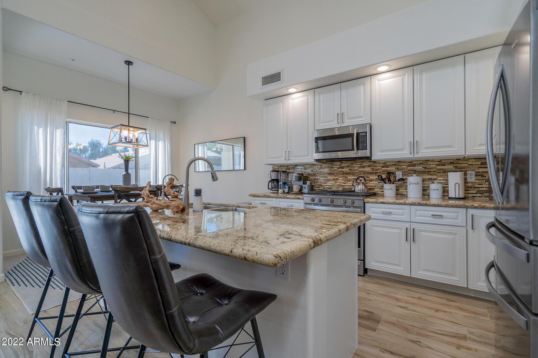 8661 East Gail Road Scottsdale, AZ 85260 - Photo 17 of 49 a kitchen with kitchen island granite countertop a sink chairs and cabinets