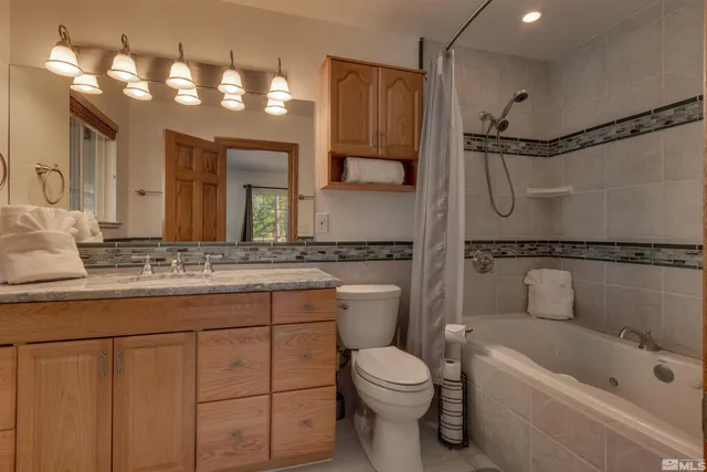 a bathroom with a granite countertop sink a toilet a mirror and shower