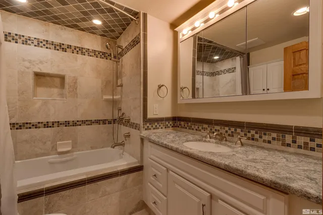 a bathroom with a granite countertop sink a mirror and a bathtub
