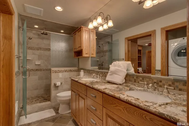 a bathroom with a granite countertop sink a toilet a mirror and shower