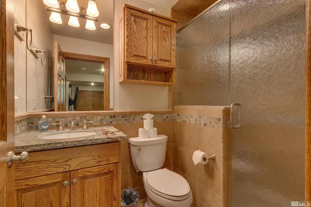 a bathroom with a granite countertop toilet sink and mirror