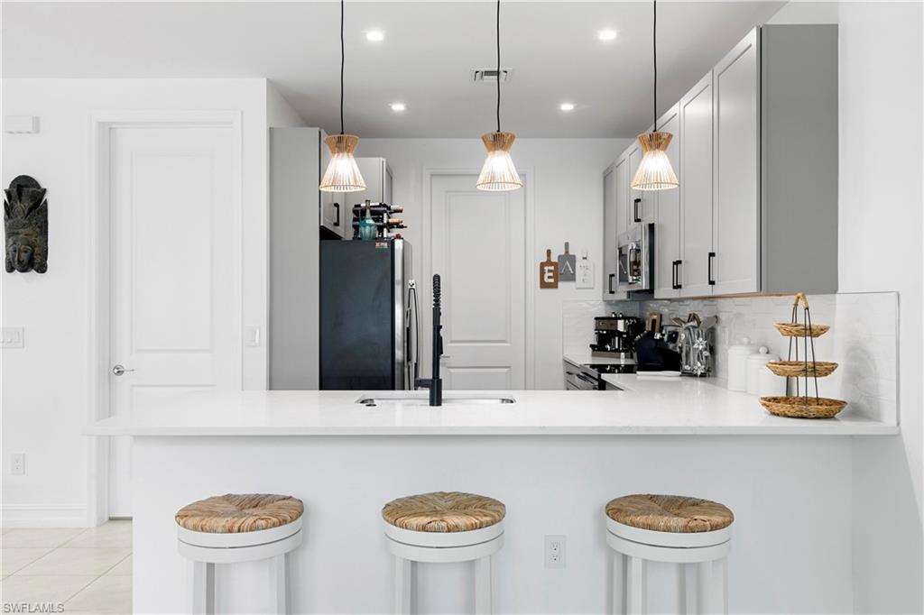 7578 Rockefeller Drive Naples, FL 34119 - Photo 14 of 39 a bathroom with a sink a large mirror and a refrigerator