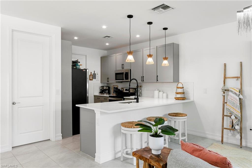 7578 Rockefeller Drive Naples, FL 34119 - Photo 17 of 39 a kitchen with stainless steel appliances granite countertop a refrigerator a sink a stove and a wooden floors