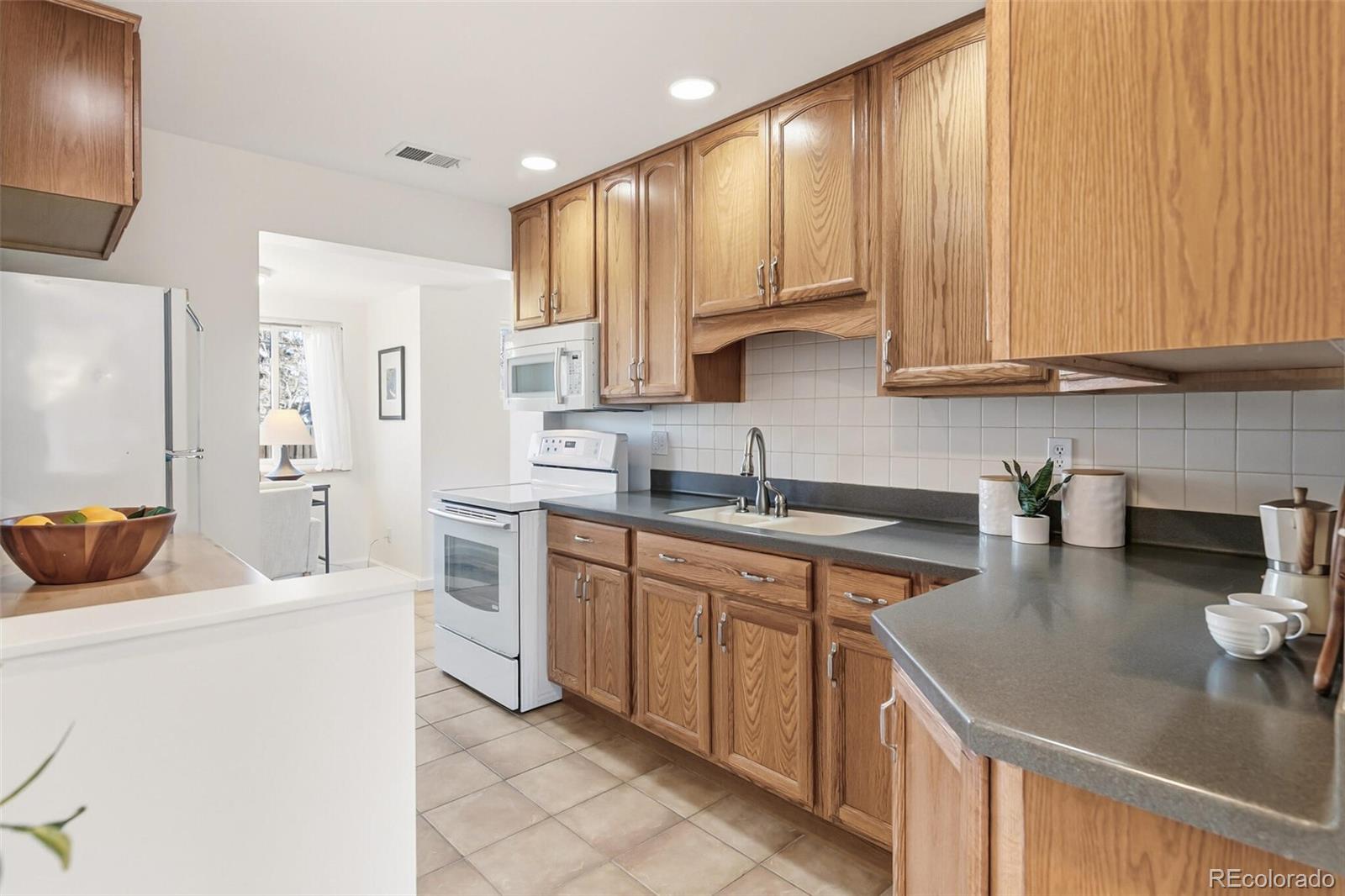 4535 Zephyr Street Wheat Ridge, CO 80033 - Photo 21 of 35 a kitchen with kitchen island granite countertop a sink a stove and white cabinets