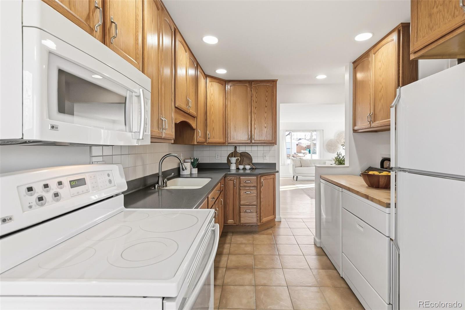 4535 Zephyr Street Wheat Ridge, CO 80033 - Photo 22 of 35 a kitchen with a sink a stove top oven and white cabinets