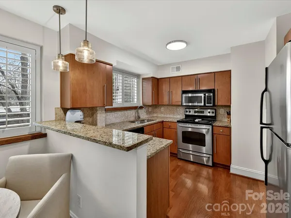 a kitchen with stainless steel appliances granite countertop a refrigerator a stove a sink dishwasher a oven with white cabinets and wooden floor