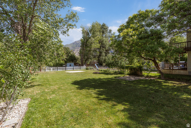146 West 200 N Street Springville, UT 84663 - Photo 24 of 29 Expansive grassy yard featuring mature trees, a white picket fence, and a distant mountain backdrop