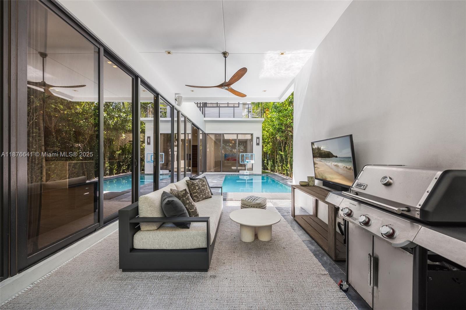 2321 Trapp Avenue Coconut Grove, FL 33133 - Photo 32 of 38 a living room with furniture a flat screen tv and a floor to ceiling window