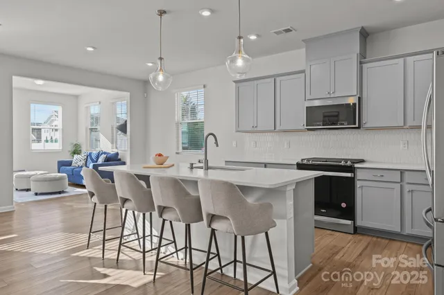 a kitchen with stainless steel appliances kitchen island granite countertop a stove top oven a sink a dining table and chairs