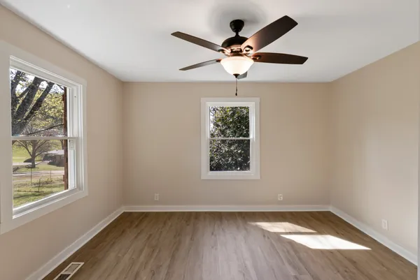 a view of an empty room with wooden floor and a window