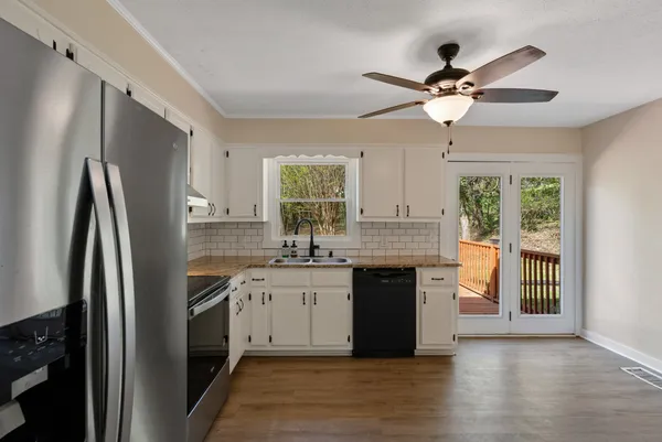 a kitchen with stainless steel appliances granite countertop a refrigerator a sink dishwasher a stove and white countertops with wooden floor