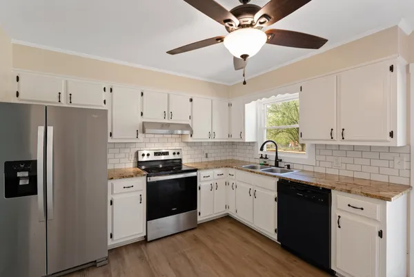 a kitchen with stainless steel appliances granite countertop a sink a stove a refrigerator cabinets and island
