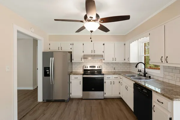 a kitchen with stainless steel appliances a sink a stove a refrigerator cabinets and wooden floor