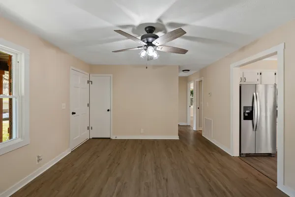 a view of an empty room with wooden floor and a window