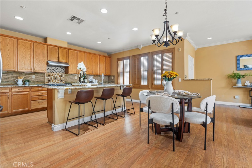 11450 Church Street, Unit 23 Rancho Cucamonga, CA 91730 - Photo 11 of 44 a kitchen with stainless steel appliances granite countertop a stove a refrigerator a kitchen island with a dining table and chairs