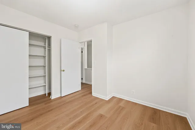 a view of an empty room with wooden floor and closet