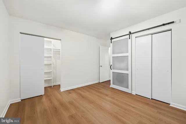 a view of an empty room with closet and wooden floor