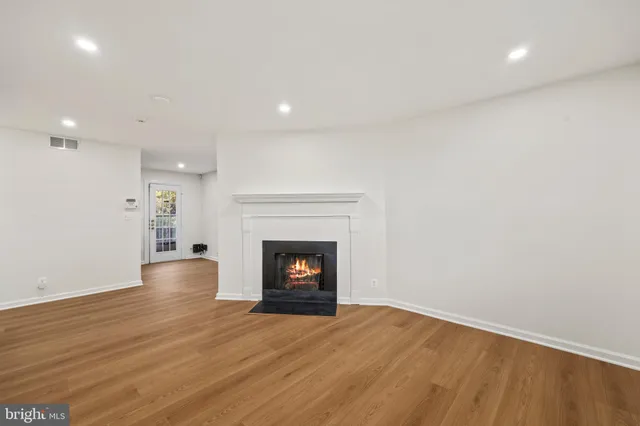a view of an empty room with wooden floor and a fireplace