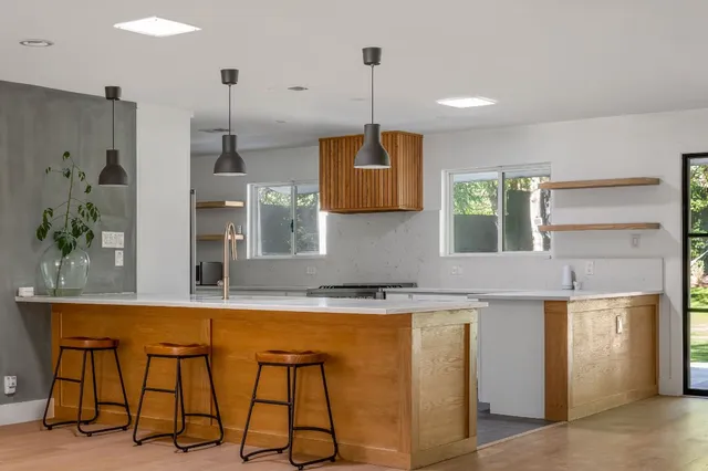 a kitchen with stainless steel appliances granite countertop a kitchen island a stove a sink a dining table and chairs with wooden floor