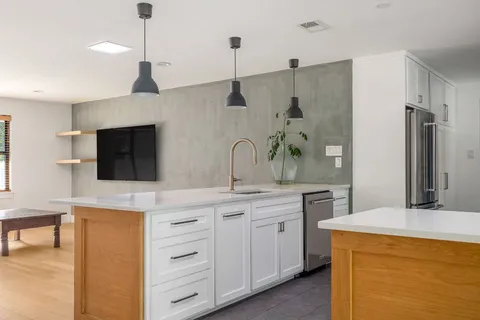 a spacious kitchen with stainless steel appliances a sink and a refrigerator