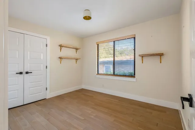 an empty room with wooden floor and windows