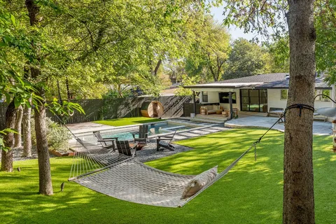 a view of a swimming pool with chairs and table in the garden