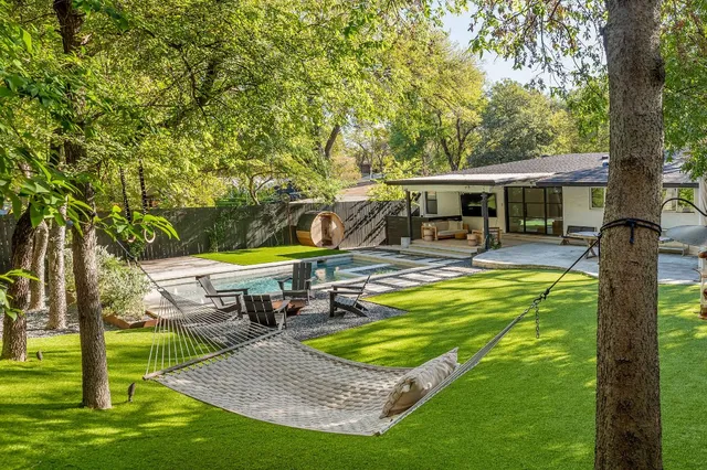 a view of a swimming pool with chairs and table in the garden