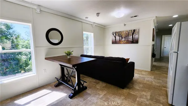 a living room with a black white checkered floor with couches chair and a large window