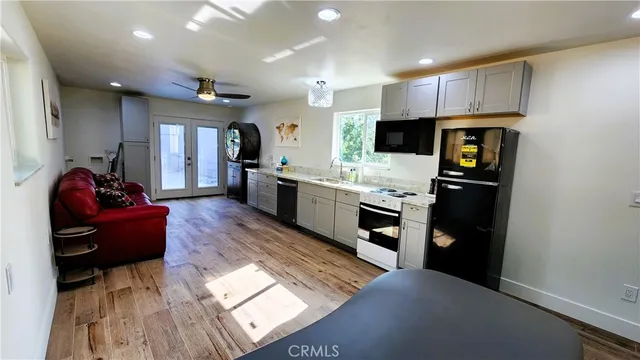 a living room with stainless steel appliances furniture a fireplace and a open kitchen view