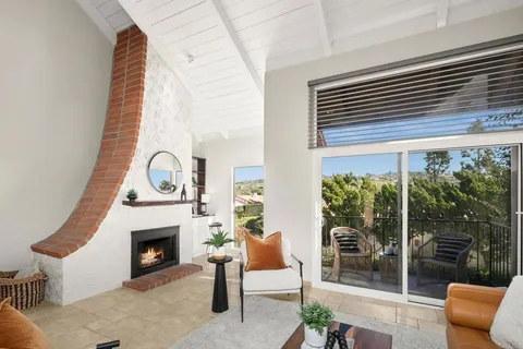 a living room with furniture a fireplace and a floor to ceiling window
