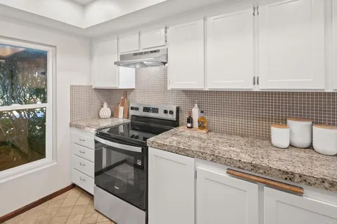 a kitchen with granite countertop a sink stove and cabinets