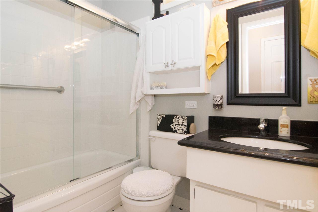 4708 Rampart Street Raleigh, NC 27609 - Photo 20 of 25 a bathroom with a granite countertop sink a toilet a mirror and shower