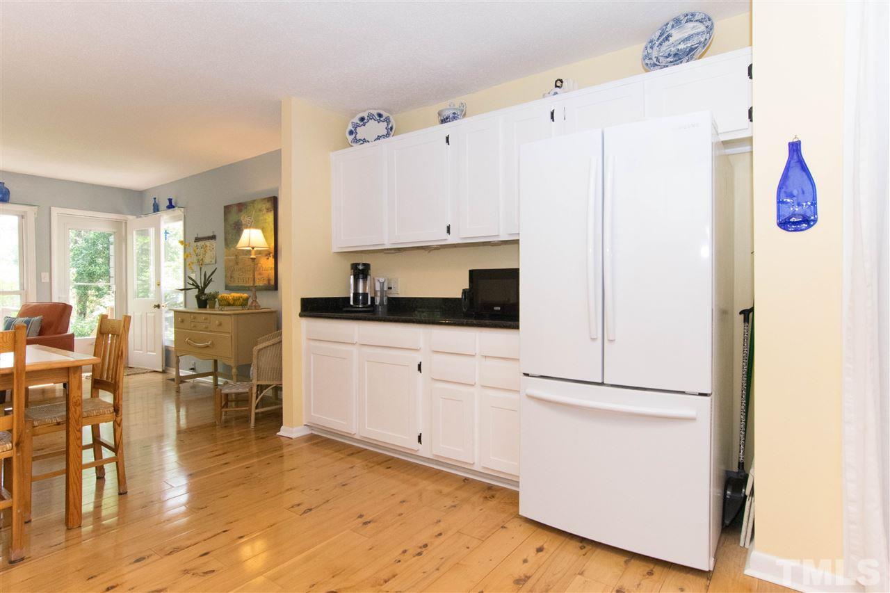 4708 Rampart Street Raleigh, NC 27609 - Photo 7 of 25 a kitchen with stainless steel appliances white cabinets and wooden floor