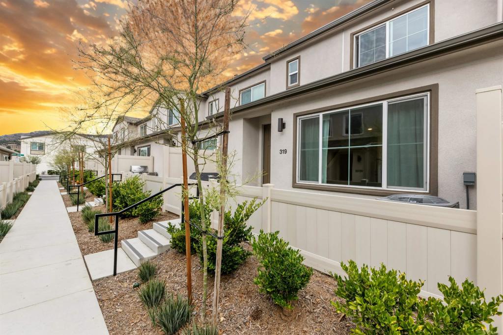 a view of a house with potted plants and a bench