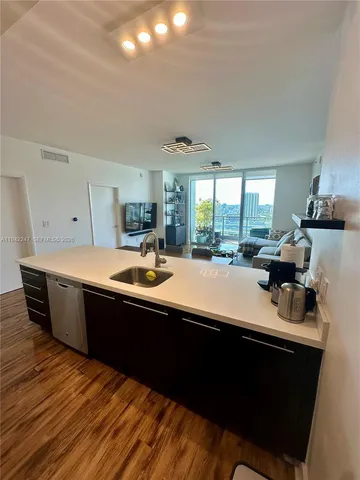a kitchen with kitchen island granite countertop a sink dishwasher stove and cabinets