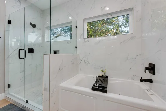 a bathroom with a tub a window and a shower