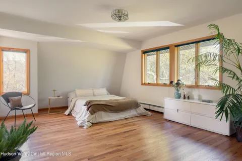 a spacious bedroom with a bed and a large window with wooden floor